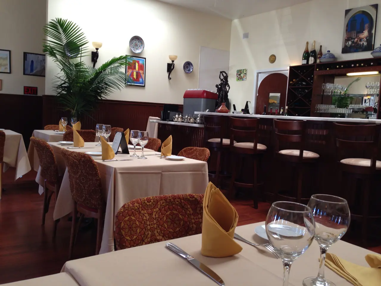 It is a restaurant there are many tables and chairs and on the table there are two glasses,napkins...