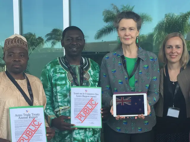 There four persons in different color dresses smiling and standing. Two of them are holding...