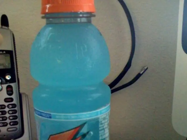 On this table there is a juice bottle with orange cap and a mobile with holder.